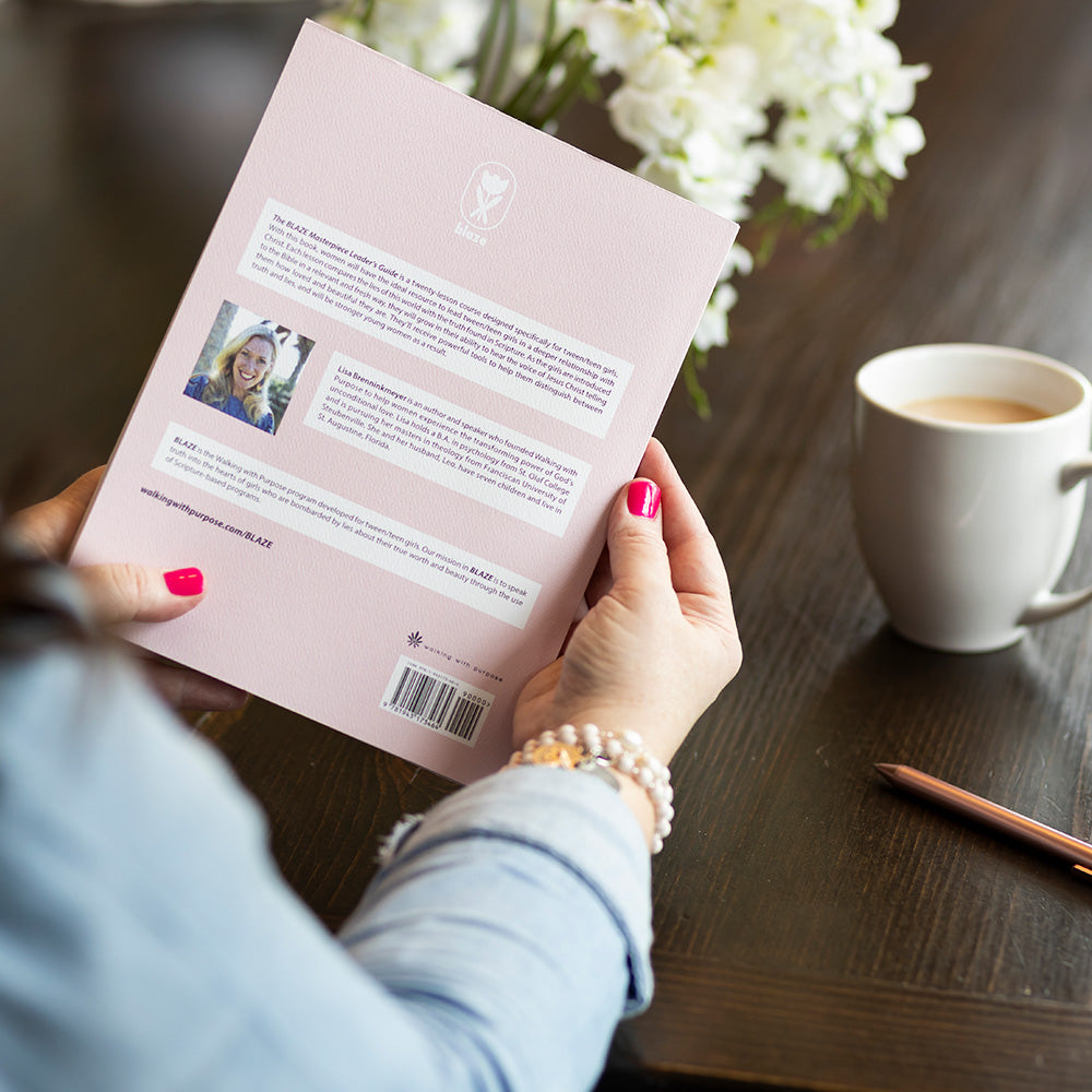 woman holding BLAZE Masterpiece leader's guide, back cover, at table