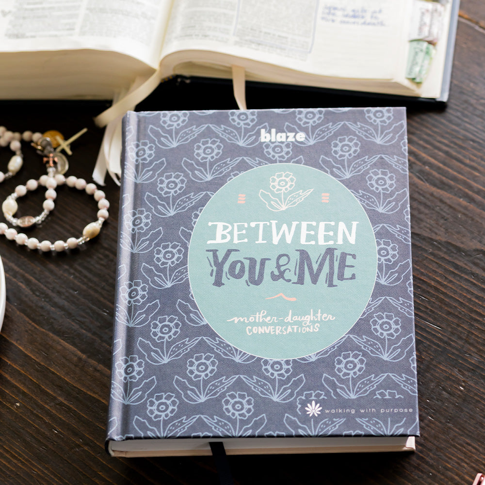 Between You and Me on table with an open Bible