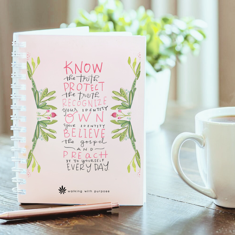 Pink notebook with Fearless and Free quote on a wooden table with a mug and flowers in the background