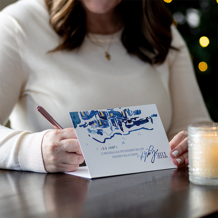 The Walking with Purpose Limited Edition Christmas Card Set features beautiful watercolor artwork in blues and yellows and the verse John 1:5: “A light shines in the darkness, and the darkness has not overcome it.” 