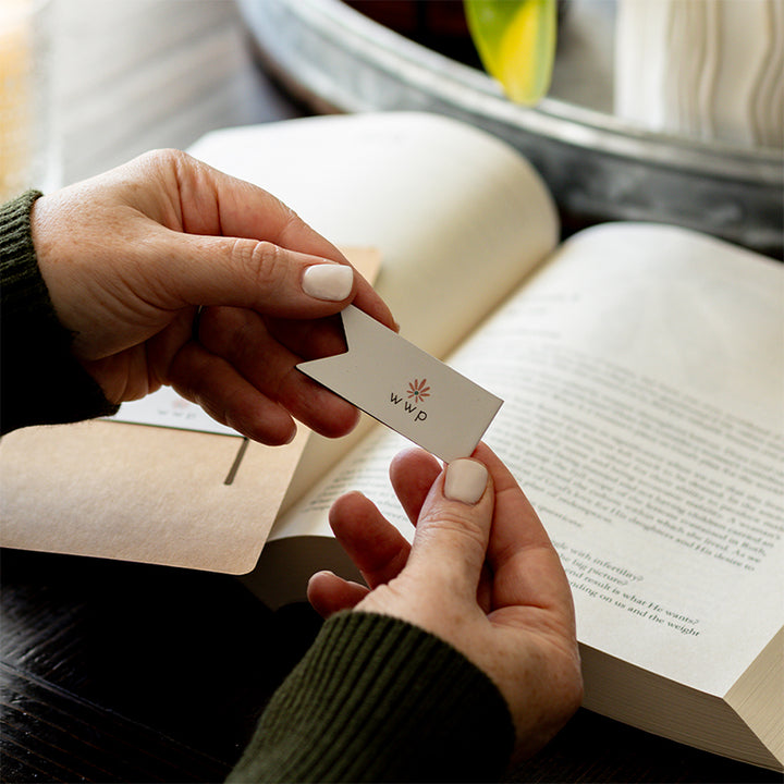 Walking with Purpose Magnetic Bookmarks designed with the signature WWP flower logo. Woman is holding one bookmark with Bible study and plant in the background.