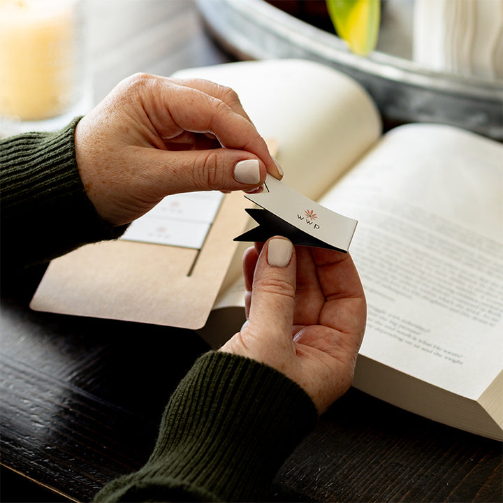 Walking with Purpose Magnetic Bookmarks designed with the signature WWP flower logo. Woman is holding one bookmark with Bible study and plant in the background.