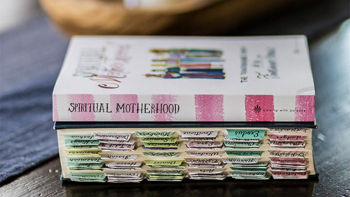 A stack of books on a dark wooden table, with the top book titled &