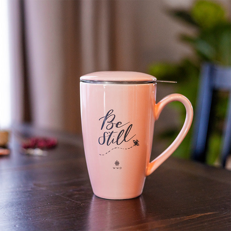 Light pink Be Still Tea Mug with Infuser and Lid on table 