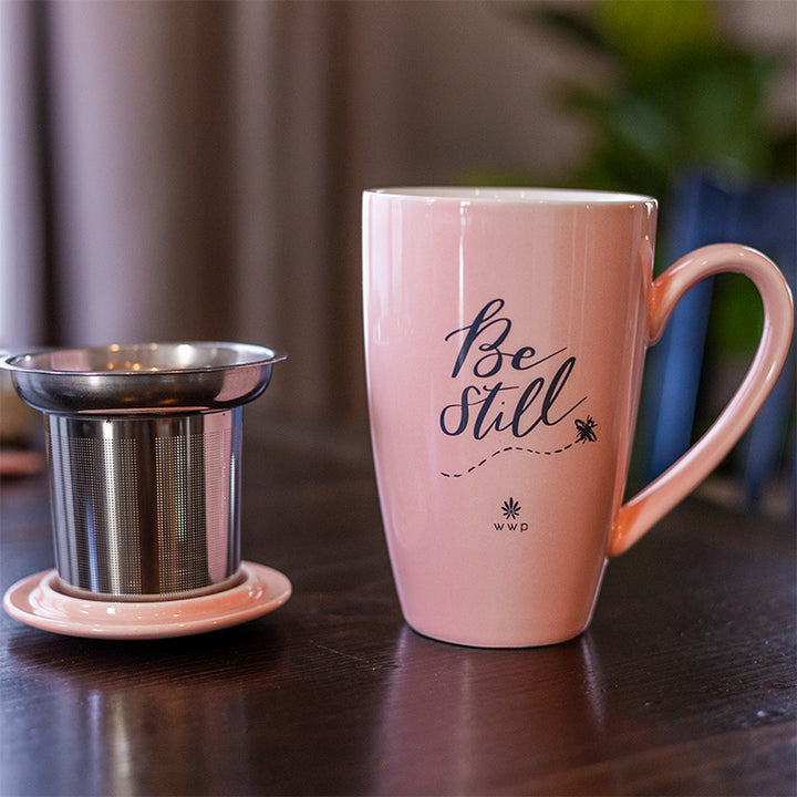 Light pink Be Still Tea Mug with Infuser and Lid on a table