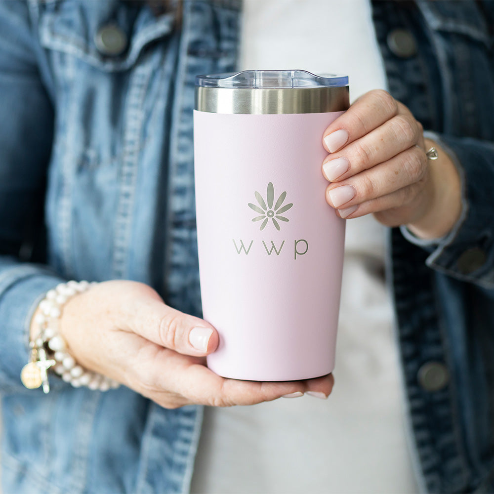 Pink tumbler with WWP flower logo on held by a woman