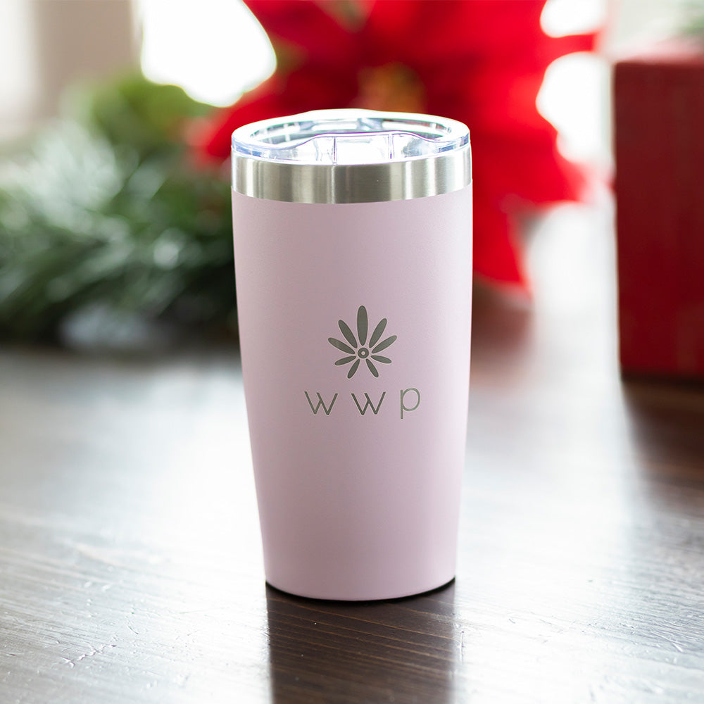 Pink tumbler with WWP flower logo on wooden table 