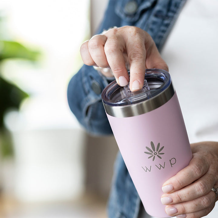 Pink tumbler with WWP flower logo with a woman demonstrating sliding the top to open